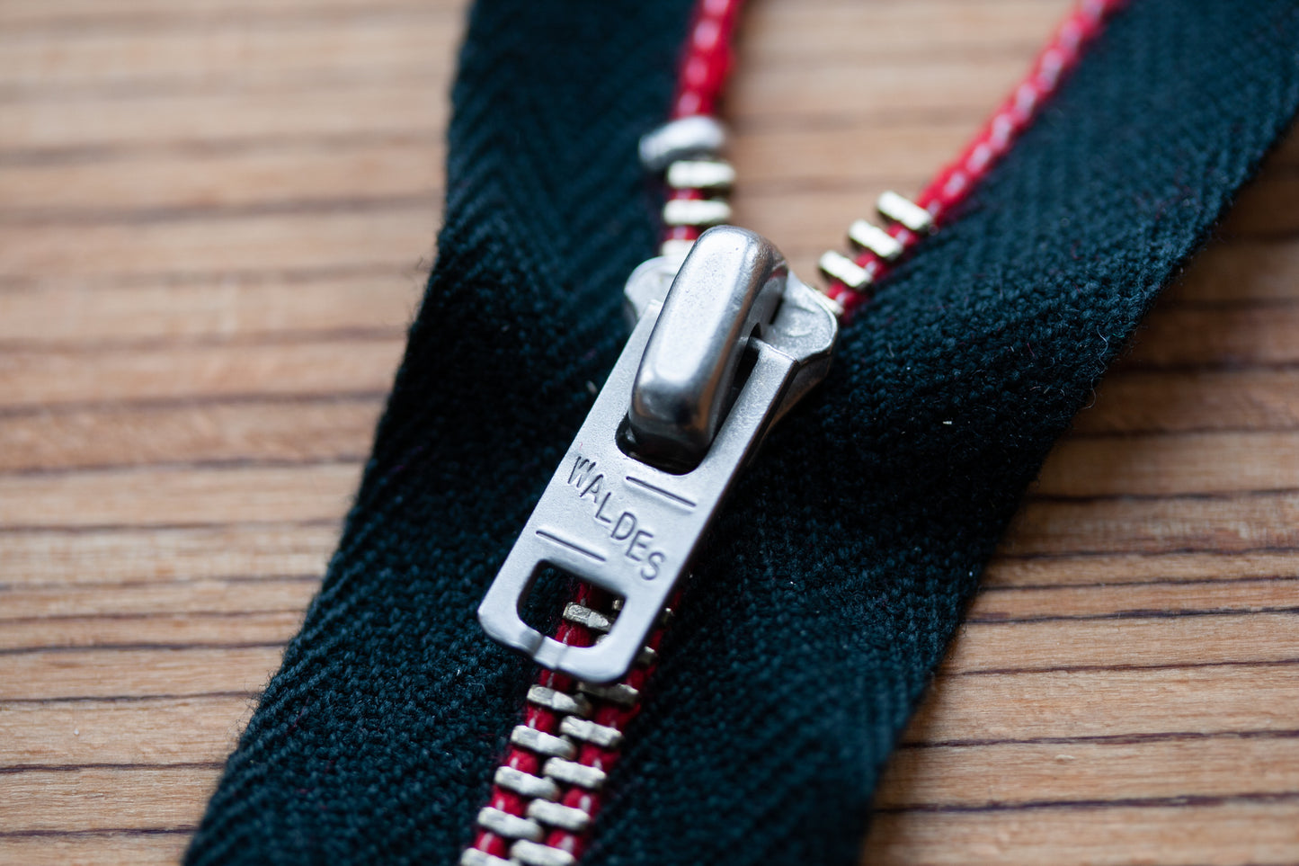 Z-003 Jeans-Reißverschluss aus Edelstahl – alternative Schieber-Ansicht mit Waldes Prägung, rote Webkante auf schwarzem Band